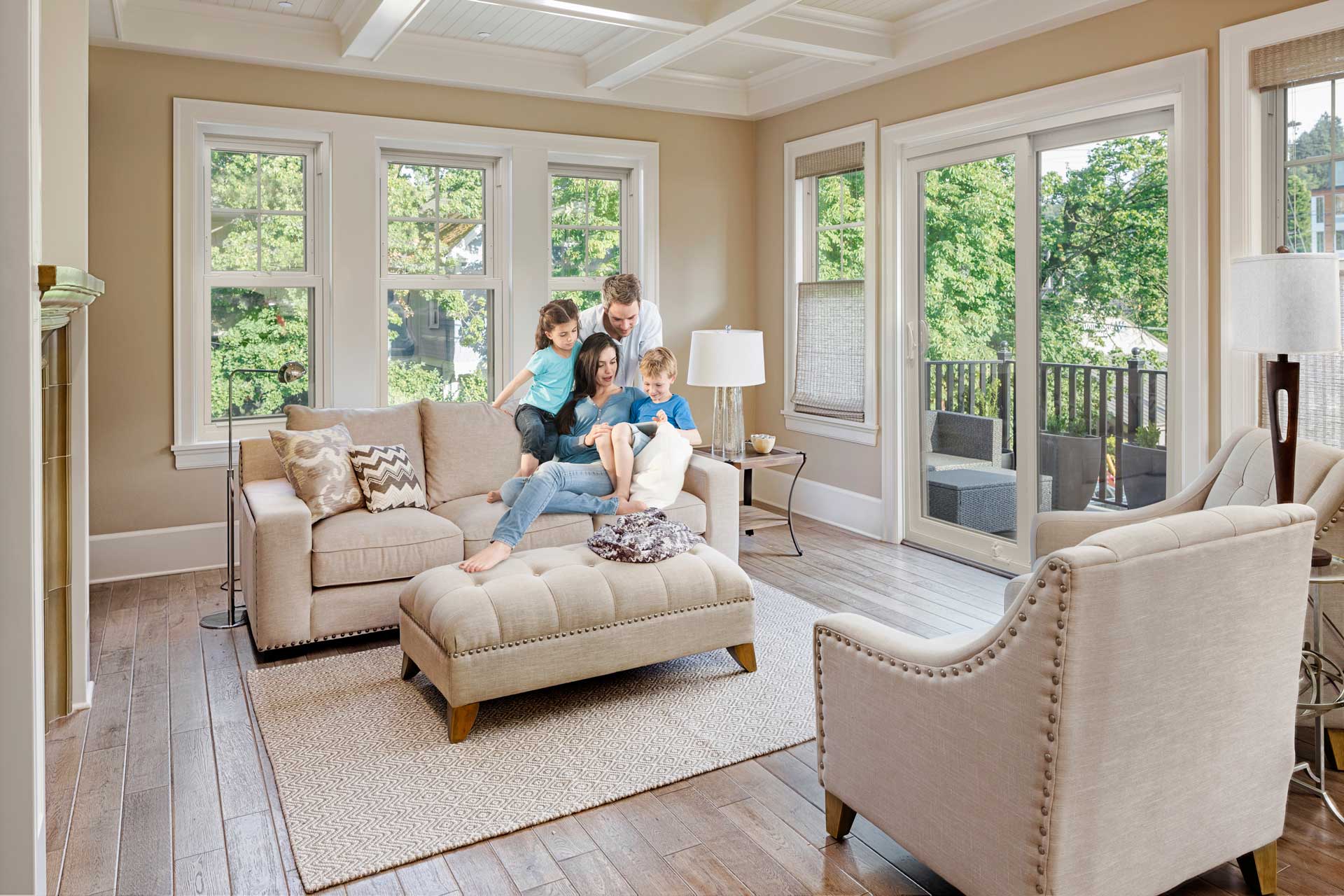 Family relaxing in a living room featuring EcoTek 1200 Series windows and sliding patio door.