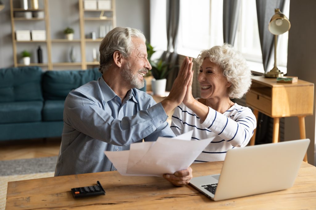 Happy senior couple celebrating home improvement financing approval from WinTek USA with a high-five.